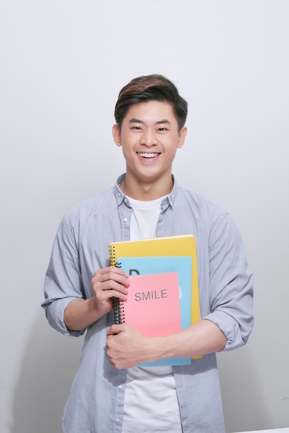 Retrato de estudante universitário sorridente feliz com livro e bolsa isolado no fundo branco