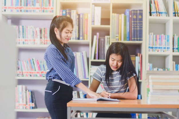 Retrato de estudantes asiáticos inteligentes fazendo pesquisa juntos na biblioteca da faculdade