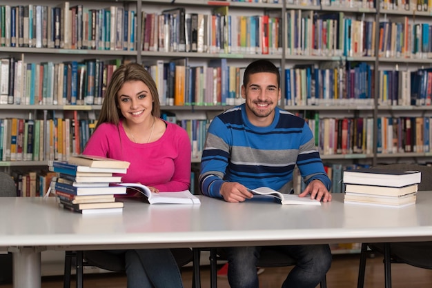 Retrato de estudantes inteligentes com livro aberto lendo na biblioteca da faculdade profundidade de campo rasa