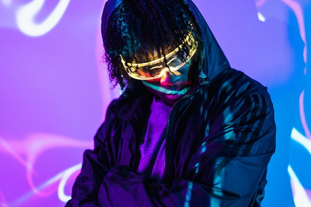 Retrato de estúdio com luzes de néon roxas e azuis de um homem em um espaço futuro usando óculos de realidade virtual