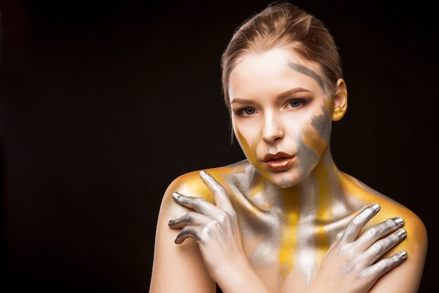 Retrato de estúdio de beleza de uma linda mulher loira com tinta ouro e prata nos ombros e rosto. Espaço para texto