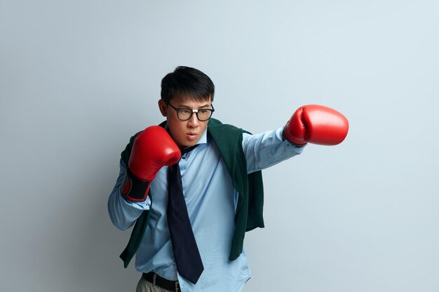 Retrato de estúdio de boxe de cara zangado de homem asiático em pé com punhos de boxe