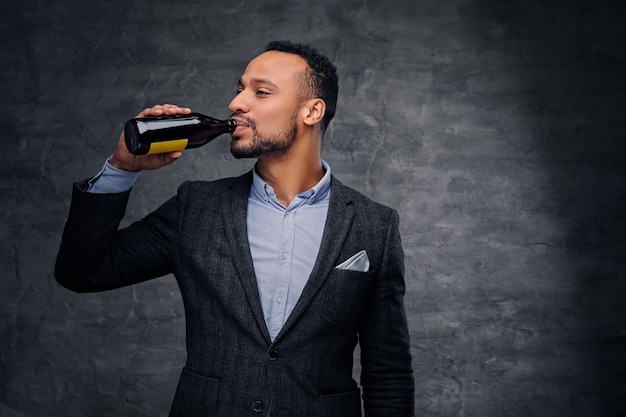 Retrato de estúdio de homem americano preto elegante vestido com uma cerveja artesanal de degustação de terno.