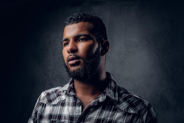 Retrato de estúdio de homem preto, barbudo, vestido com uma camisa de lã.