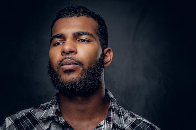 Foto retrato de estúdio de homem preto, barbudo, vestido com uma camisa de lã.