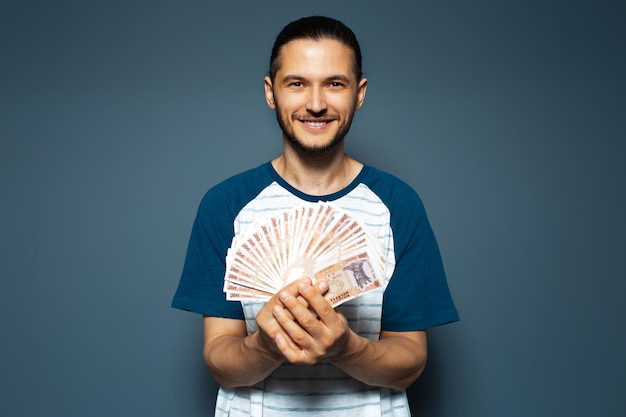 Retrato de estúdio de homem sorridente segurando dinheiro monte de notas da Moldávia leu