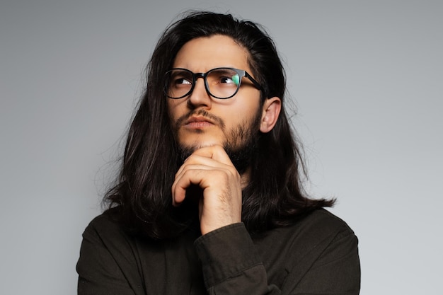 Retrato de estúdio de jovem atraente pensativo com cabelo comprido