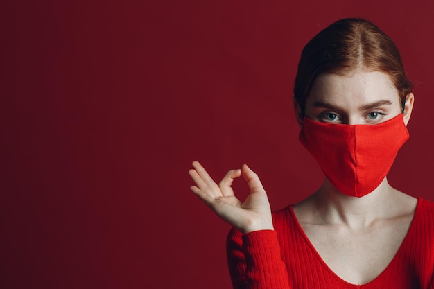 Retrato de estúdio de jovem com máscara protetora médica isolada em fundo vermelho Yoga calma zen e meditação um conceito de pandemia covid19