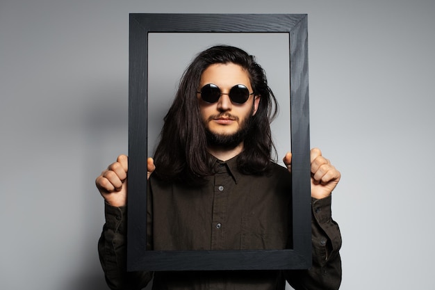 Retrato de estúdio de jovem segurando o porta-retrato vazio de preto