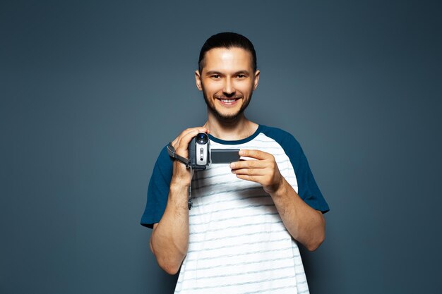 Retrato de estúdio de jovem sorridente com câmera de vídeo digital nas mãos