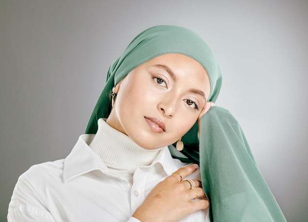 Retrato de estúdio de linda mulher muçulmana isolada contra um fundo cinza Jovem mulher vestindo hijab ou lenço na cabeça mostrando a modéstia árabe tradicional segurando as mãos juntas e olhando para a câmera