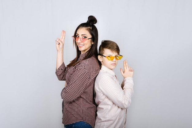 Retrato de estúdio de mãe de família feliz e filho adolescente em óculos coloridos se divertindo