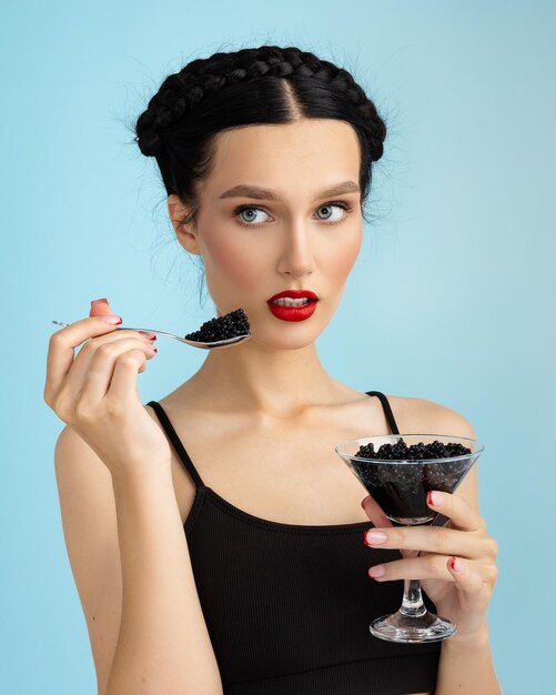 Foto retrato de estúdio de moda de uma bela mulher com cabelo castanho comendo caviar