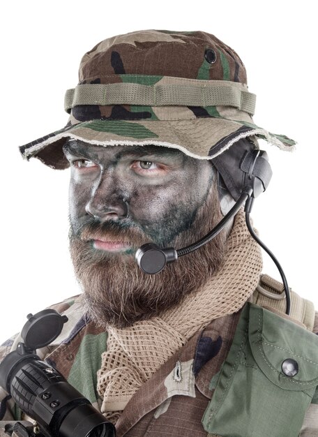 Retrato de estúdio de ombro de soldado de comando, mercenário moderno, soldado profissional com tinta de camuflagem preta no rosto barbudo, fone de ouvido tático de rádio com microfone, isolado no fundo branco