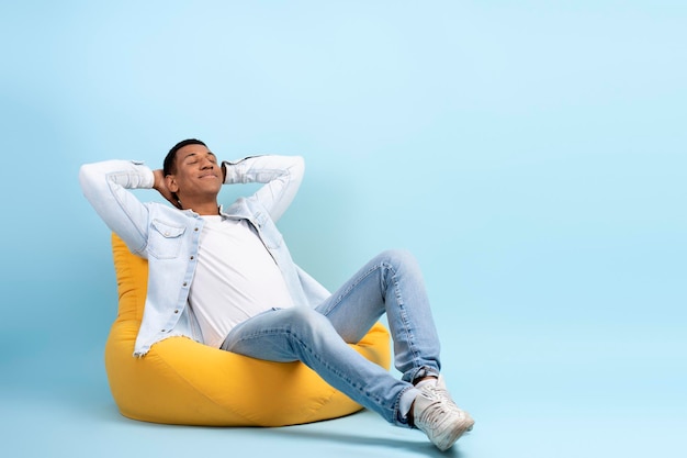 Retrato de estúdio de poltrona relaxante relaxado homem alegre isolado na parede azul