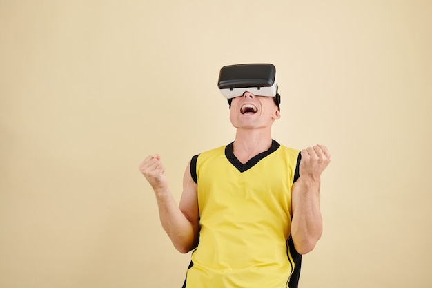 Retrato de estúdio de um homem com óculos de realidade virtual gritando ao ganhar no videogame