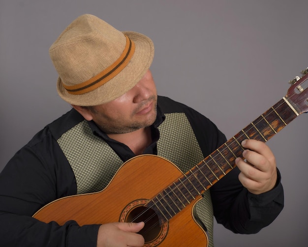 Retrato de estúdio de um homem usando um chapéu tocando um velho tres cubano