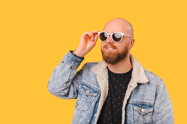 Retrato de estúdio de um jovem homem bonito barbudo careca usando óculos de sol legais