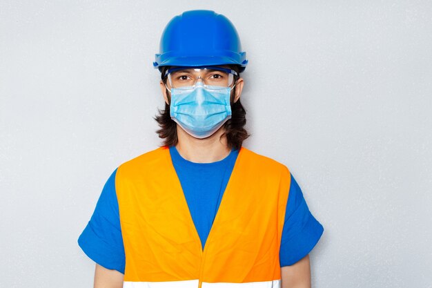 Foto retrato de estúdio de um jovem trabalhador da construção civil com máscara médica contra coronavírus e covid-19