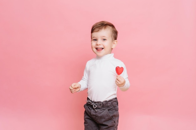 Retrato de estúdio de um menino feliz com um pirulito em forma de coração