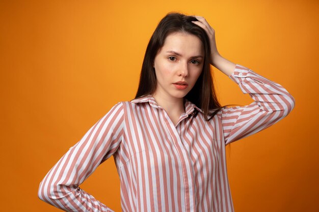 Retrato de estúdio de uma jovem bonita pensando contra um fundo amarelo