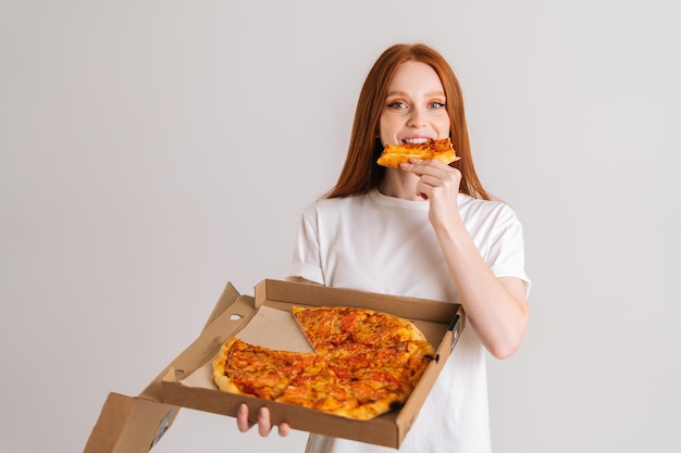 Retrato de estúdio de uma jovem feliz com apetite para comer uma deliciosa pizza segurando a caixa nas mãos