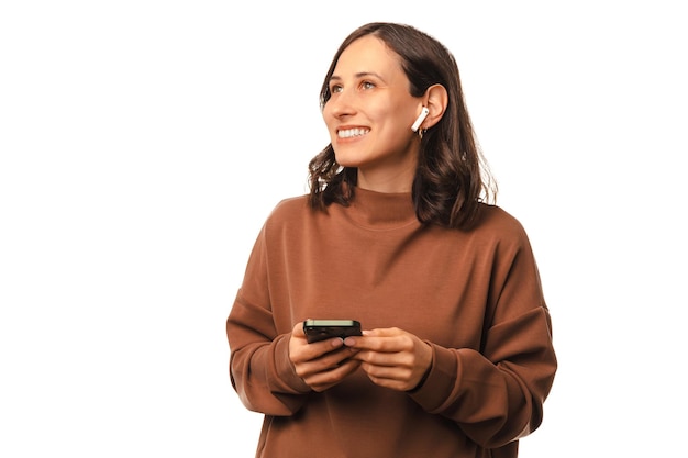 Retrato de estúdio de uma jovem usando fones de ouvido brancos e segurando o telefone