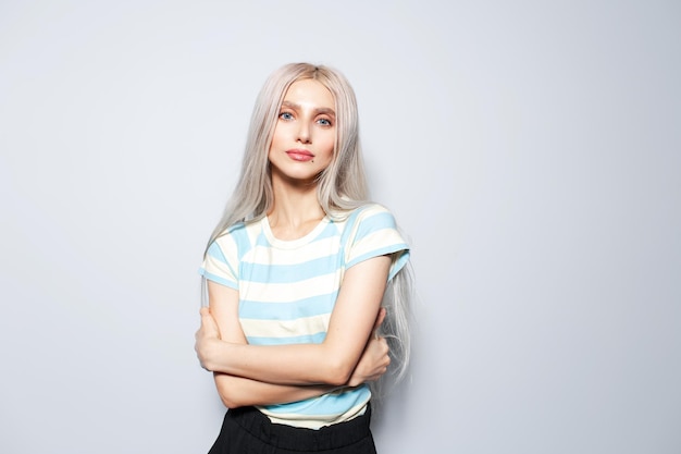 Retrato de estúdio de uma linda garota loira em camisa listrada em fundo branco