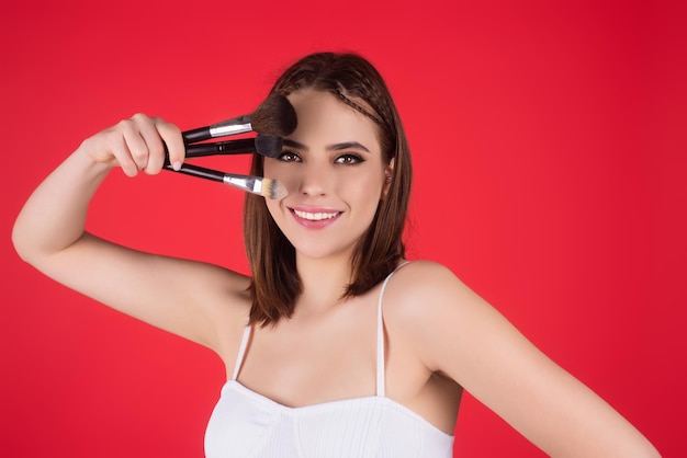Retrato de estúdio de uma mulher aplicando base cosmética no rosto usando um lindo pincel de maquiagem