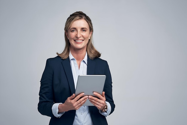 Retrato de estúdio de uma mulher de negócios madura usando um tablet digital contra um fundo cinzento