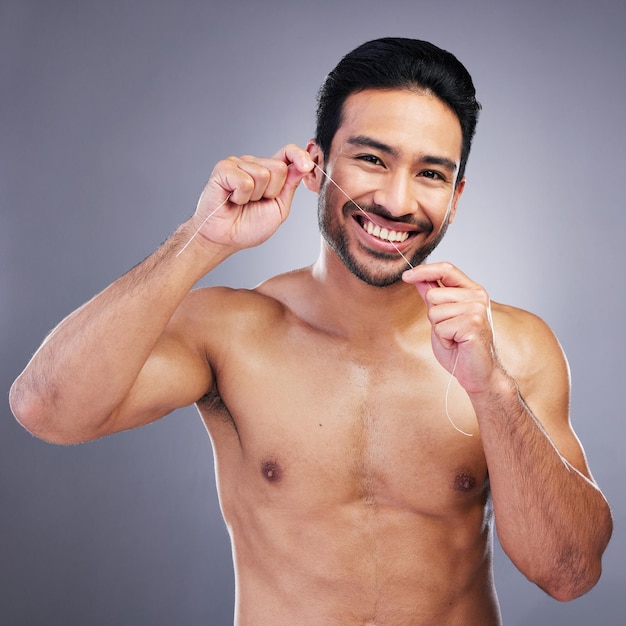 Retrato de estúdio de uso do fio dental ou homem feliz com saúde bucal higiene bem-estar ou cadeia de tratamento dentário rotina matinal sorriso estético ou pessoa de atendimento odontológico em fundo cinza