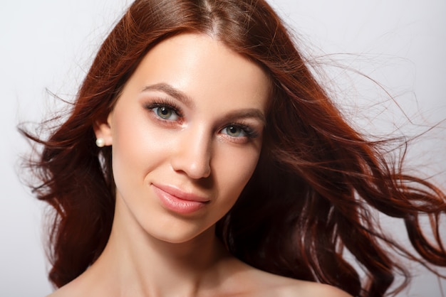 Retrato de estúdio glamour de uma linda mulher com cabelos de luxo em um fundo claro.