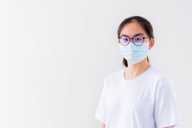 Retrato de estúdio Mulher jovem asiática usa óculos e máscara para se proteger contra o Coronavírus, olhando para a câmera.