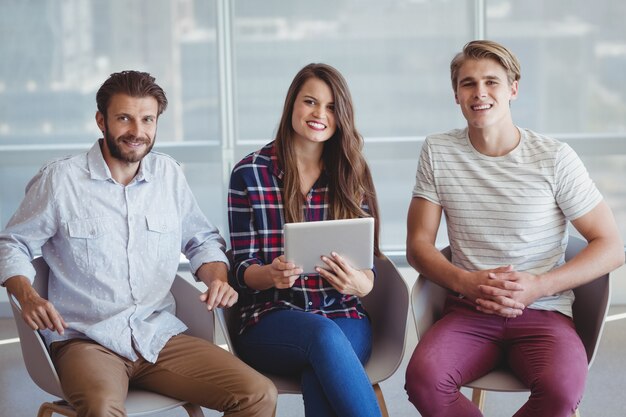 Retrato de executivos de negócios, sentado na cadeira do escritório e usando tablet digital