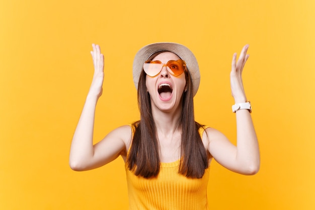 Retrato de expressiva mulher gritando triste chateada em copos laranja, espalhando as mãos, mantendo a boca bem aberta, olhando para cima isolado no fundo amarelo. Conceito de emoções sinceras de pessoas. Área de publicidade