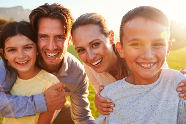 Retrato de família branca feliz abraçando ao ar livre retroiluminado