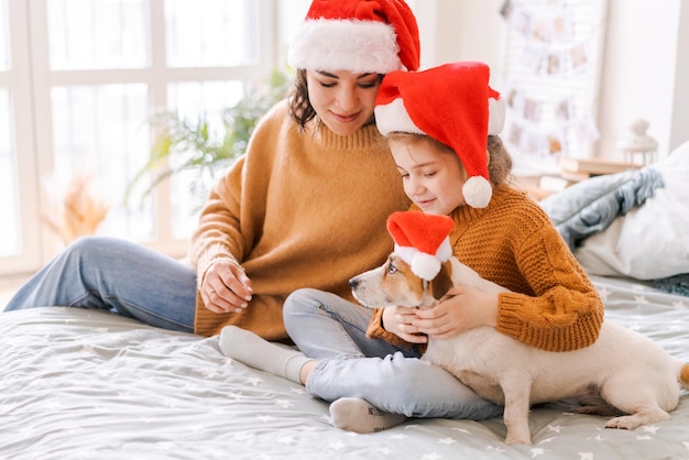 Retrato de família caucasiana feliz em chapéus de Papai Noel para o Natal com um cão jack