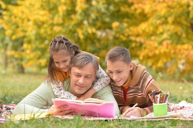 Retrato de família descansando no parque com livro