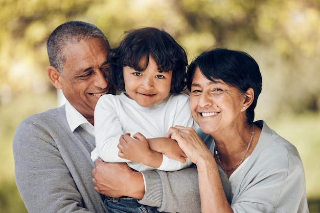 Retrato de família e abraço de criança e avós em um parque com vínculo de cuidado e diversão em fundo desfocado Sorriso de amor e rosto de idosos abraçando a liberdade de aposentadoria com uma criança em uma floresta