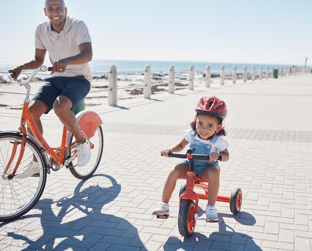 Retrato de família e andar de bicicleta na praia com a menina e o pai na bicicleta feliz e sorrir enquanto aprende a se relacionar e se divertir Bicicleta de família feliz e pai com filho no mar para passeio na natureza