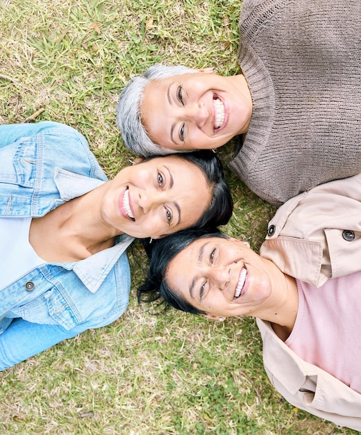 Retrato de família e mãe avó e filha adulta relaxam na grama felizes e se unem em um jardim gerações de rosto e mulheres se divertindo rindo e aproveitando o fim de semana em um parque juntos