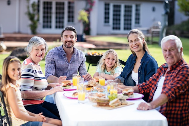 Retrato de família feliz almoçando no jardim