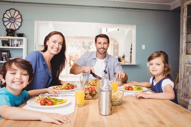 Foto retrato de família feliz com comida na mesa de jantar