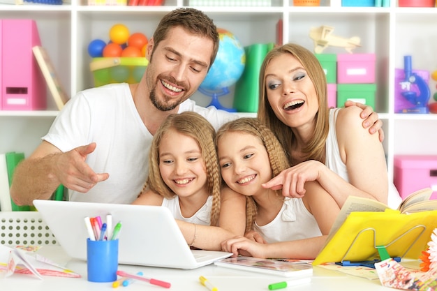 Retrato de família feliz com laptop em casa