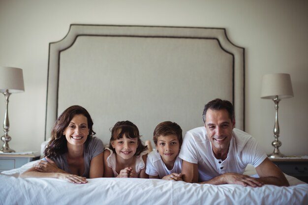 Retrato de família feliz, deitado na cama no quarto