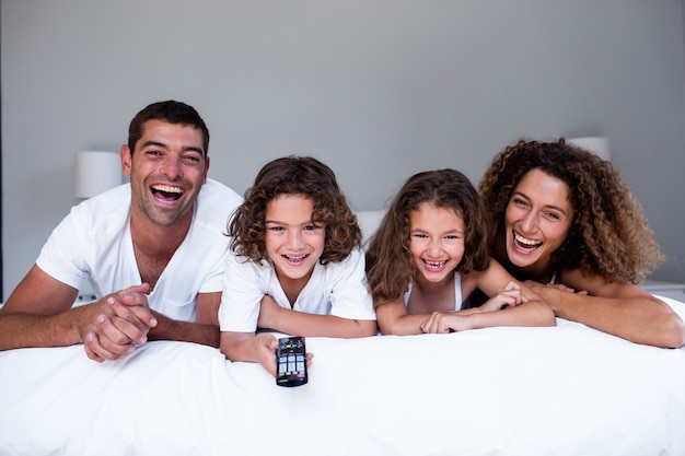 Retrato de família feliz, deitado na cama