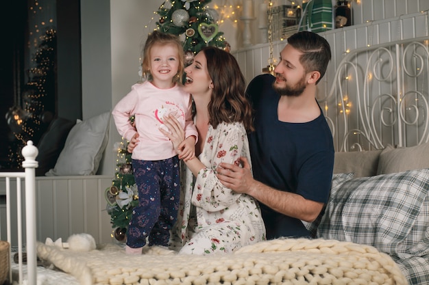 Retrato de família feliz fofo de pijama no natal na cama