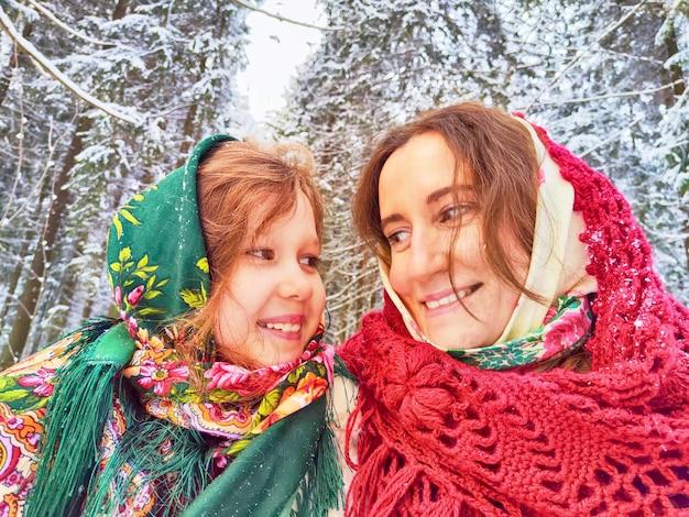 Retrato de família feliz mãe e filha em xales na floresta de inverno roupas étnicas para