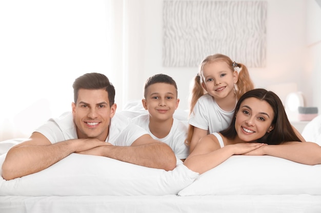 Retrato de família feliz na cama grande no quarto