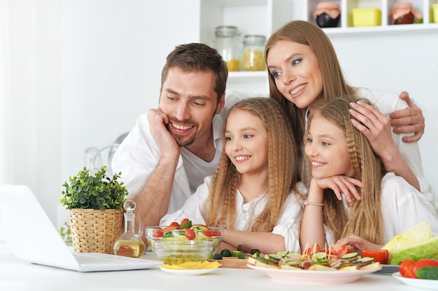 Retrato de família feliz na cozinha com laptop